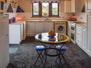 a kitchen with a table with a bowl of fruit on it at Lakeland Bungalow in Oulton