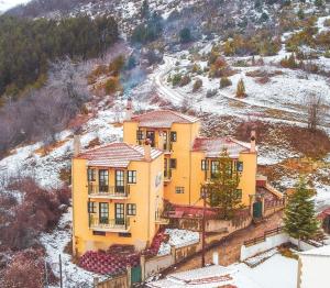 an aerial view of a yellow house in the snow at Muses Apartments in Pisoderi
