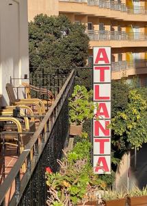 un panneau d'hôtel avec des tables, des chaises et des plantes dans l'établissement Hostal Atlanta, à El Arenal