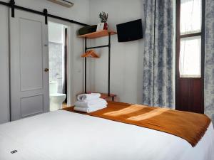 1 dormitorio con cama blanca y ventana en La Piquera Hostal, en Córdoba