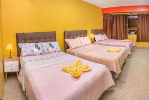 2 camas en una habitación con paredes amarillas en Hotel Royal, en Ica