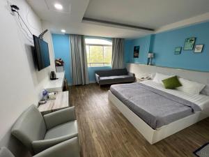 a bedroom with blue walls and a bed and a couch at Nouveau Happy Inn - Bến Thành in Ho Chi Minh City