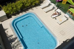 einen Blick über den Pool mit einer Person, die auf einem Stuhl vor dem Pool sitzt in der Unterkunft Hotel Milano in Cesenatico