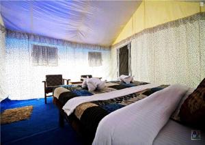 a hotel room with two beds and a table at Desert Oasis Camp in Hundar