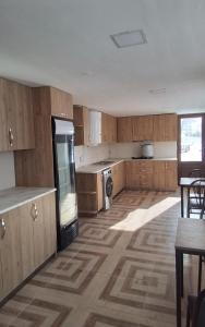 a large kitchen with wooden cabinets and a table at Agro House Mezge - აგროსახლი მეზგე in Bashkʼo
