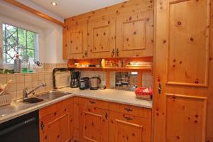 a kitchen with wooden cabinets and a sink at Chesa Sonnenuhr in Madulain