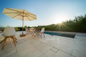 eine Terrasse mit einem Tisch, Stühlen und einem Sonnenschirm in der Unterkunft Dimora Manfredo Eco B&B Luxury in San Nicola Arcella