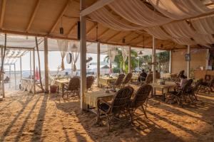 a restaurant with tables and chairs under a tent at Cuba Patnem in Patnem