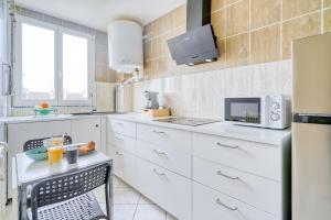 a kitchen with white cabinets and a microwave at My Cosy Home 1 in Vitry-sur-Seine