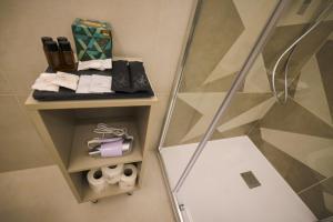a bathroom with a shower and a shelf with towels at Brettia Guest Rooms in Cosenza