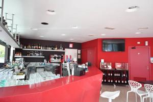 a red bar with white chairs and a red wall at Aparthotel Alessandria in Lignano Sabbiadoro