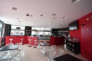 un restaurante con paredes rojas, mesas y sillas blancas en Aparthotel Alessandria en Lignano Sabbiadoro