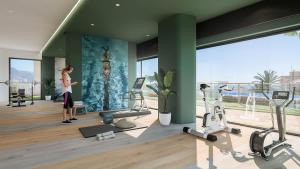 a woman standing in a gym with exercise equipment at ROMERO APARTMENTS SUNSET CLIFFS BENIDORM in Benidorm
