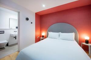 a bedroom with a red wall and a white bed at Free Parking - Roof Terrace - Luxury Townhouse in Manchester