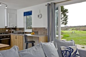 eine Küche und ein Wohnzimmer mit einem Sofa und einem Tisch in der Unterkunft Wheal Tor- Beautifully Fitted Wooden Lodge Helston Cornwall in Helston