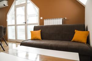 uma sala de estar com um sofá castanho com almofadas amarelas em Miadora apartments - Apartma Bela štorklja em Moravske-Toplice