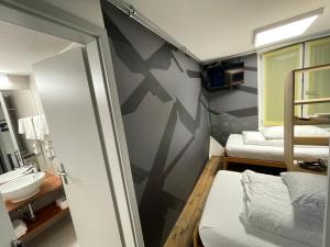 a room with a bathroom with a sink and a mirror at Hotel16 by Messe & Stadion Suisse in Minuten & Late Check-in in Bern