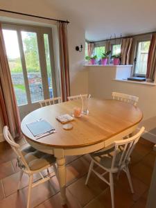 a wooden table with chairs and a laptop on it at The Long Barn in Baltonsborough