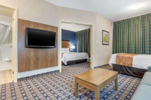 a hotel room with two beds and a flat screen tv at Quality Suites in Whitby