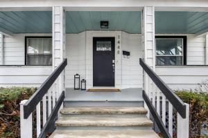 a white house with a blue door and stairs at The Lakewood Belle: Family Friendly Home 10 minutes to Downtown! in Cleveland