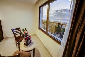 una habitación con una mesa y una ventana con flores. en AQABA COAST HOTEL en Áqaba