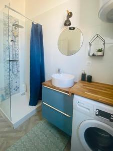 a bathroom with a sink and a washing machine at Sur les toits de Nîmes in Nîmes