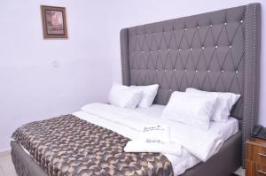 sypialnia z łóżkiem z białą pościelą i poduszkami w obiekcie Akure Airport Hotel w mieście Oba Ile