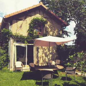 a table with an umbrella in front of a house at Chai Gascon in Termes-dʼArmagnac
