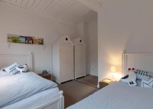 a white bedroom with two beds and two wardrobes at von-Deska-Countryhouses-Kapitaens-Fluegel in Nieblum