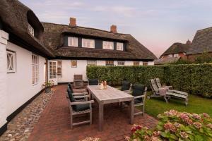 a patio with a table and chairs in front of a house at von-Deska-Countryhouses-Reeder-Fluegel in Nieblum