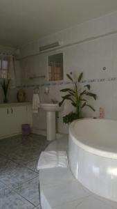 a white bathroom with a tub and a sink at Harmony Guesthouse in Nelspruit