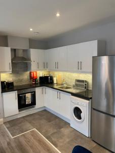 a kitchen with white cabinets and a stainless steel refrigerator at Cosy and central Abbey Street Apt in Dublin