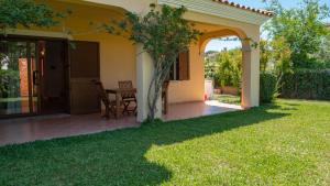 a patio with a table and chairs on a lawn at Casa Vacanza la Suaredda in San Teodoro