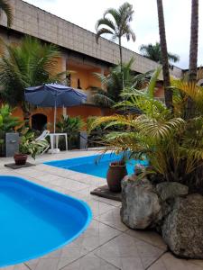 uma piscina em frente a um edifício com palmeiras em Pousada Boramar em Boraceia