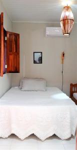 a bedroom with a white bed with a fan at Casa de Praia in Coroa Vermelha