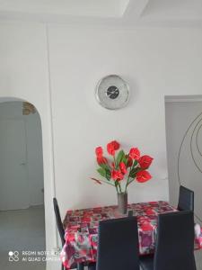 una mesa con un jarrón con flores rojas. en L'étonnant F3 Joris, en Saint-Pierre