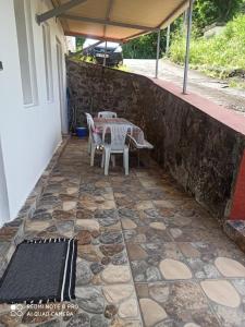 eine Terrasse mit einem Tisch und Stühlen an einer Steinmauer in der Unterkunft L'étonnant F3 Joris in Saint-Pierre