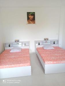 two beds in a white room with a picture on the wall at L'étonnant F3 Joris in Saint-Pierre