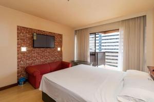 a bedroom with a white bed and a red couch at Flat Particular Hotel Kubitschek in Brasilia +93 photos