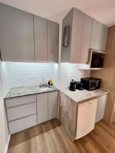 una pequeña cocina con armarios blancos y fregadero en Estudio - apartamento cómodo y acogedor SS1 en Córdoba