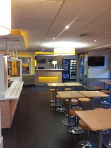 un restaurante de comida rápida con mesas y taburetes en ibis Budget Gennevilliers Asnieres, en Gennevilliers