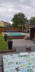 a patio with a table and chairs and a pool at Location 24 heures du Mans auto in Parigné-lʼÉvêque