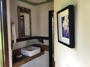 ein Bad mit einem Waschbecken und einem Spiegel in der Unterkunft Chalés Vista das Montanhas in Lavras Novas