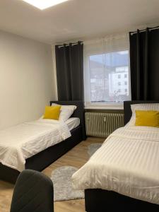 2 Betten mit gelben Kissen in einem Zimmer mit Fenster in der Unterkunft Apartment 33 in Bad Hönningen