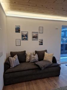 eine Couch in einem Wohnzimmer mit Bildern an der Wand in der Unterkunft Appartement Lurger in Kirchberg in Tirol