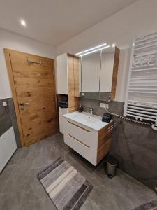 La salle de bains est pourvue d'un lavabo blanc et d'une porte en bois. dans l'établissement Appartement Lurger, à Kirchberg in Tirol