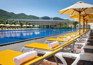 a row of tables with umbrellas next to a swimming pool at Oceanami Resort Sea View in Long Hai