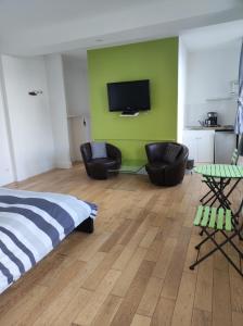 a bedroom with a bed and two chairs and a flat screen tv at Les Galets Bleus in &Eacute;tretat