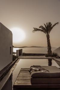 - une piscine avec un lit et un palmier dans l'établissement Casa Cook Mykonos - Adults Only, à Ornos