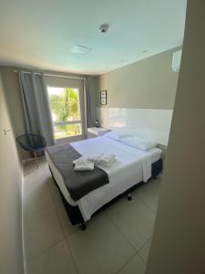 Un dormitorio con una cama grande y una ventana en Flat Guarajuba, Charmoso Porto Smeralda en Guarajuba